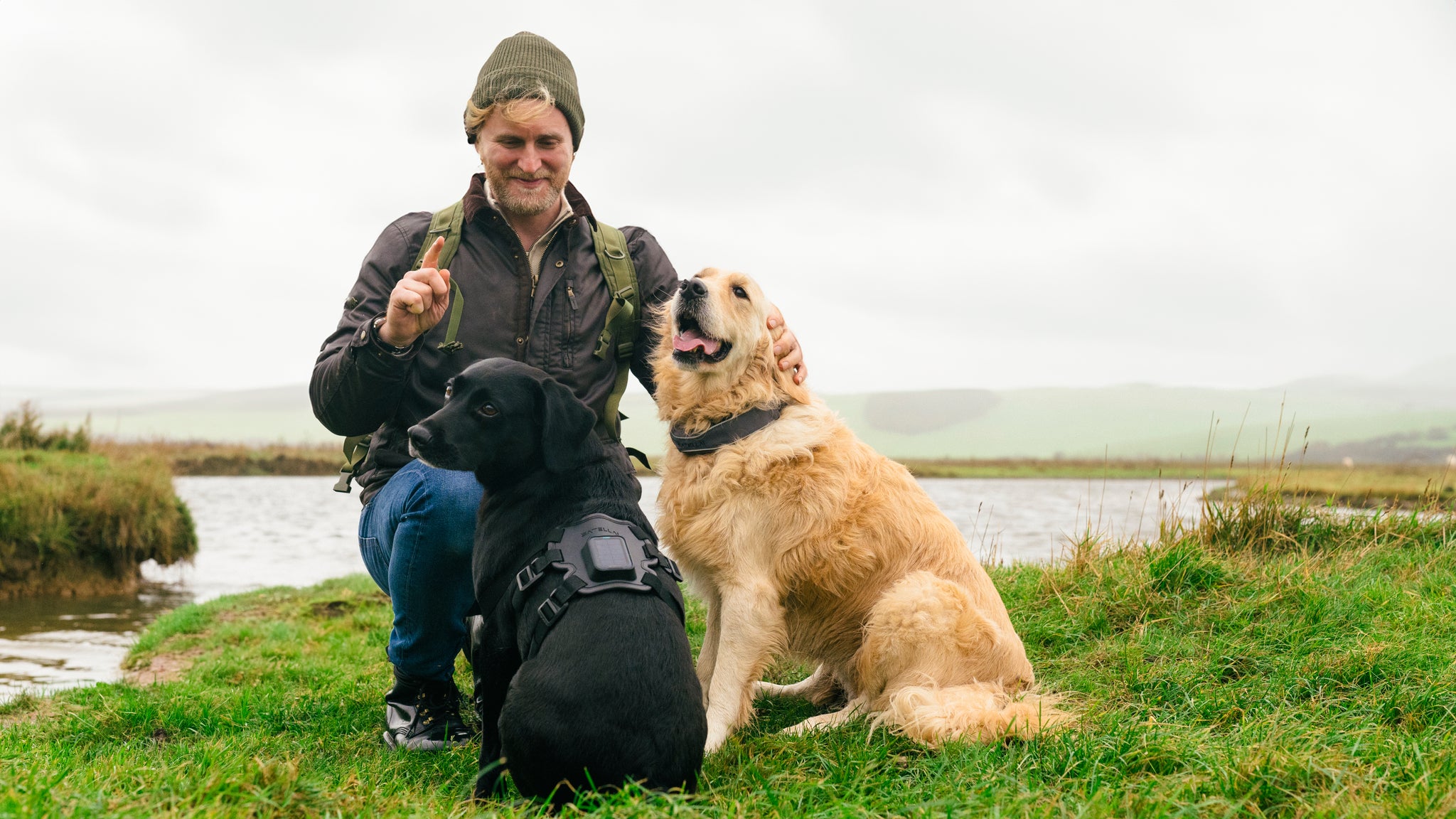 Owner with two dogs wearing GPS tracking collars during an outdoor hike by the water