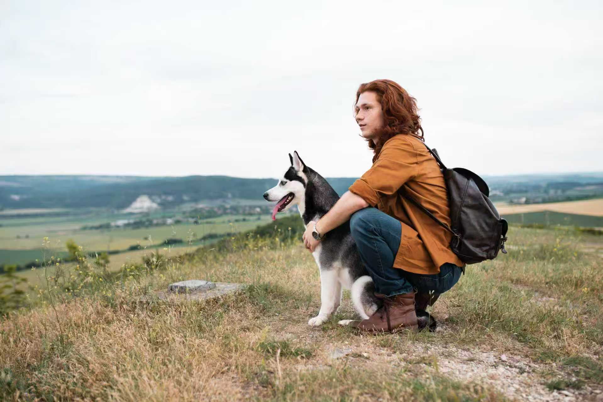 Man hiking with his Siberian Husky on a scenic hilltop